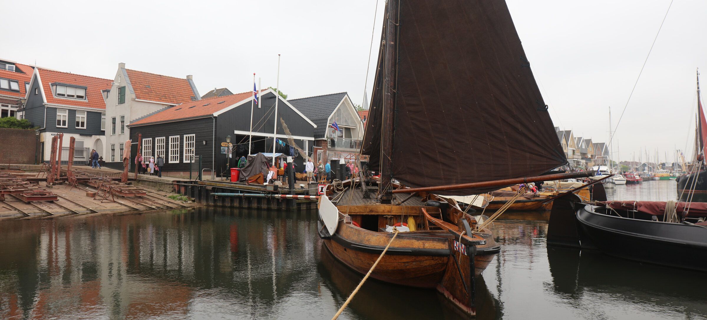 Een Urker botter met bruin zeil aan de kade bij de botterschuur